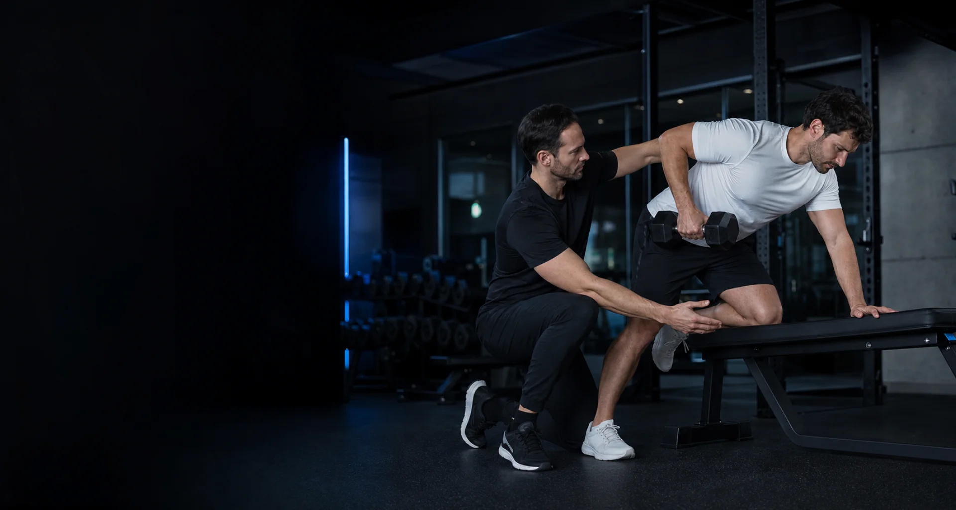 Personal Trainer begleitet einen Kunden beim Kurzhanteltraining